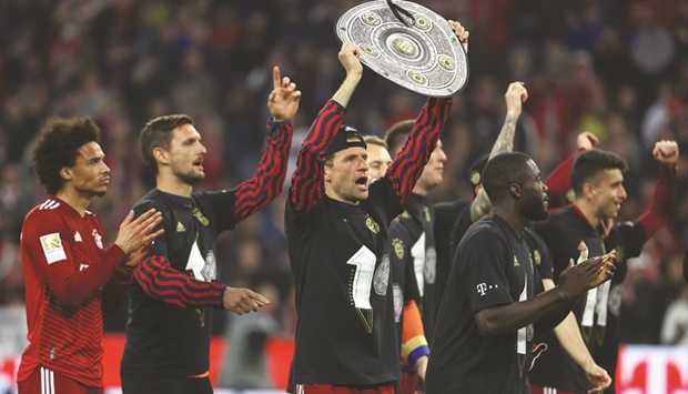 Bayern Munich's Thomas Muller celebrates with a replica trophy and teammates after winning the Bundesliga