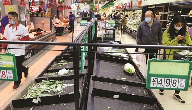 Customer wearing a face masks walks next to near-empty shelves at a supermarket following the Covid-19 outbreak in Chaoyang district of Beijing, China, yesterday.