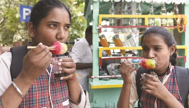 Schoolgirls enjoy an ice popsicle during a hot summer day in Amritsar, India, yesterday.