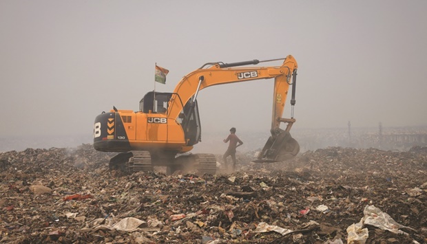 An excavator tries to contain the fire as smoke billows from burning garbage on a hot summer day, at the Bhalaswa landfill site in New Delhi, India.