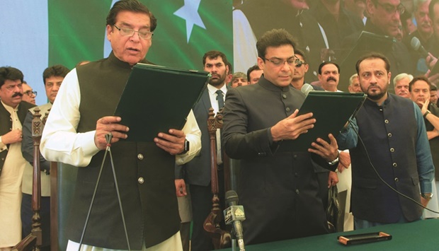 This handout photograph released by Punjab Press Information Department shows the Speaker of the National Assembly, Raja Pervez Ashraf (left), administering the oath to Hamza Shehbaz Sharif (centre), son of Prime Minister Shehbaz Sharif, as the chief minister of Punjab province.
