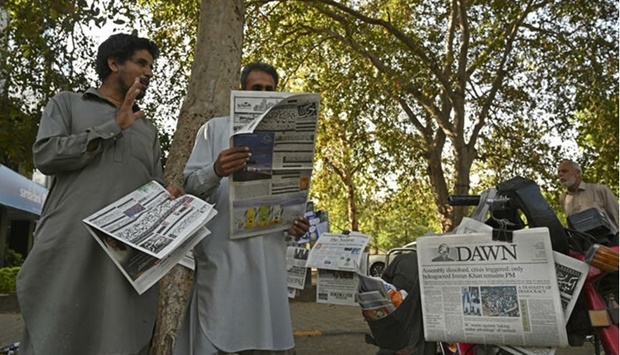 Residents look at the morning newspapers displayed for sale at a roadside stall in Islamabad on April 4, 2022, a day after Pakistan Prime Minister Imran Khan foiled an attempt to boot him from office by getting the president to dissolve the national assembly, meaning fresh elections must be held within three months