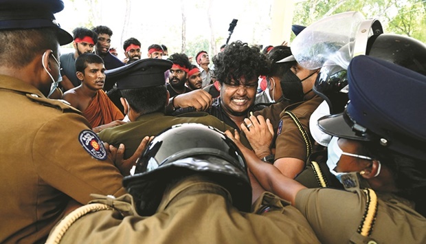 Police officers scuffle with a medical student as he protests along with others against Sri Lankau2019s crippling economic crisis outside the health ministry in Colombo yesterday.