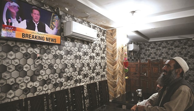 A man listens to Prime Minister Khan addressing the nation on television at a restaurant in Islamabad.