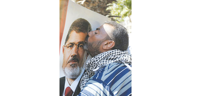 A protester supporting Egyptu2019s deposed president kisses a poster of Mohamed Mursi during a demonstration near the Republican Guard barracks in Cairo y