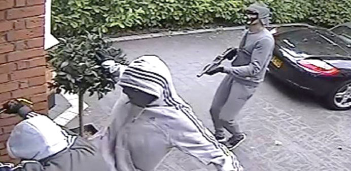 The men break down the door as one wields a shotgun.