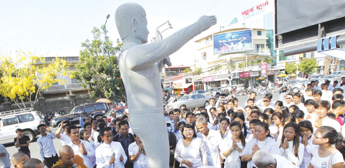 Cambodian workers pray next to a statue of former president of the Free Trade Union of the workers of Cambodia Chea Vichea during a ceremony in Phnom 
