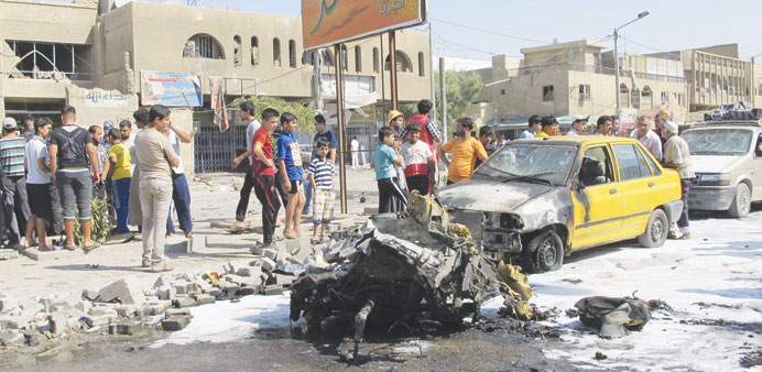 Residents gather at the site of a car bomb attack in Baghdadu2019s Hurriya district yesterday.