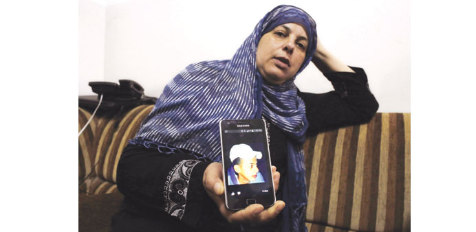 Suha, mother of Mohamed Abu Khadr, shows a picture of her son on her mobile phone at their home in Shuafat. Inset: Naftali Fraenkel.