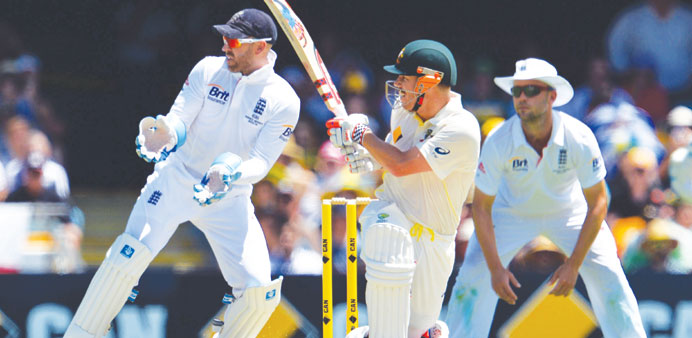    Australian batsman David Warner (C) plays a shot as Englandu2019s wicketkeeper Matt Prior (L) looks on during day three of the first AshesTest at the G