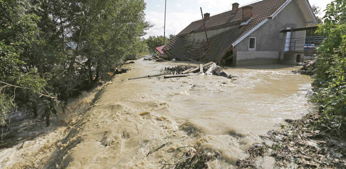 Flood waters flow past a house in Novaci, southwest Romania.