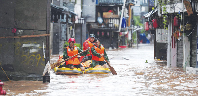 Rescue workers search for people down a flooded street in Fenghuang, Hunan province.