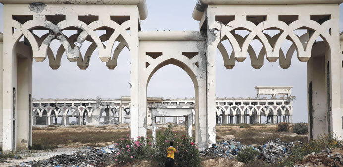 A boy picks flowers in front of the destroyed and deserted main gate of the Gaza stripsu2019 former international airport.