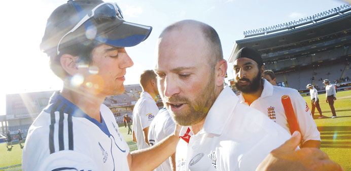 England captain Alastair Cook hugs teammate Matt Prior as Monty Panesar watches after they save the Test against New Zealand in Auckland yesterday. (R