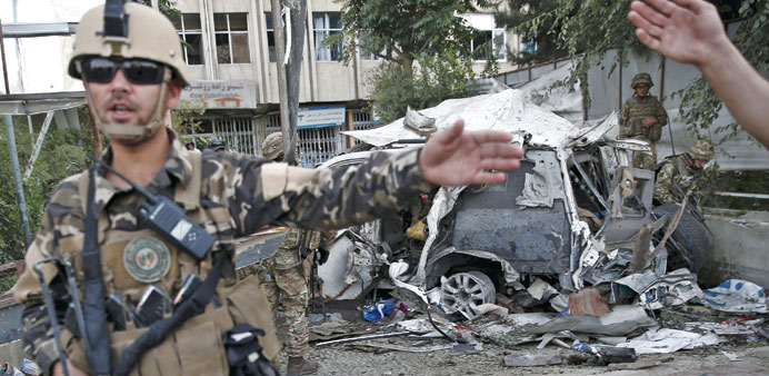 Members of Afghan security forces keep watch in front of a damaged car that belongs to foreigners after a bomb blast in Kabul, yesterday.