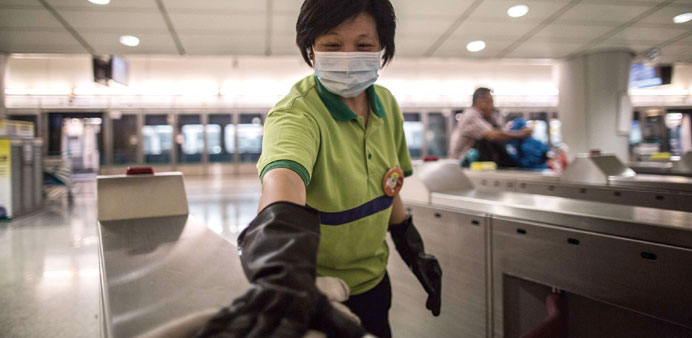 A masked member of the staff cleans a ticket turnstile near a train platform at Kowloon station in Hong Kong yesterday after a 17-year-old Korean male