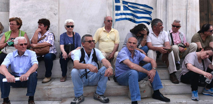Pensioners sit in front of the Bank of Greece's headquarters during a protest to reclaim their pensions in central Athens 