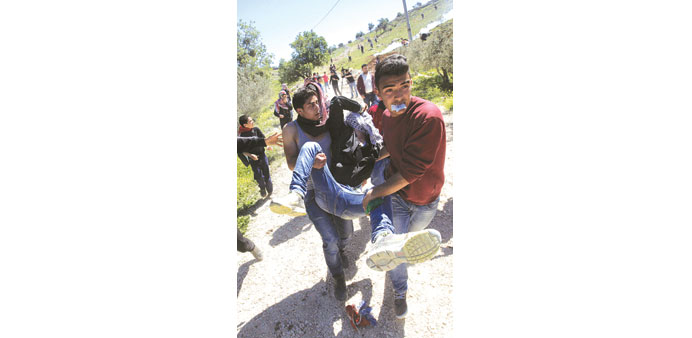 Palestinian protesters carry an injured demonstrator following clashes with Israeli security forces in the West Bank village of Burin yesterday.