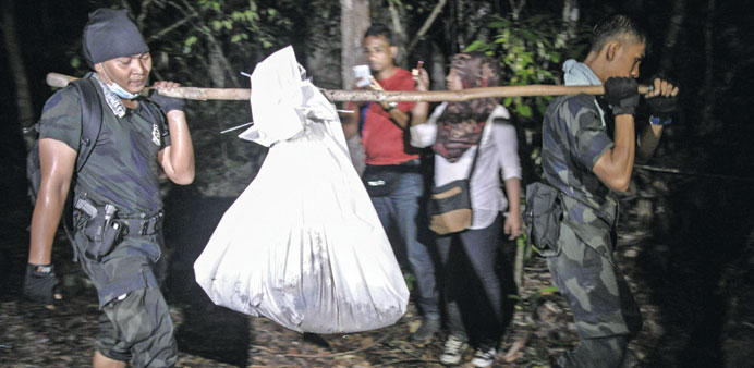 Royal Malaysian Police carry exhumed human remains from the jungle in the Malaysian northern state of Perlis.