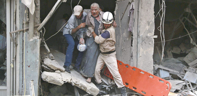 Civil defence members help a man injured in a barrel bomb attack by regime forces in the Shaar neighbourhood of Aleppo on Sunday.