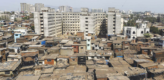 High-rise residential buildings are seen behind a cluster of houses at a slum in Mumbai.