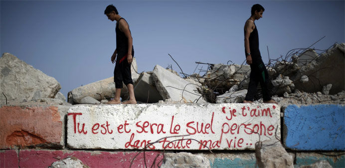 Palestinians walking on a wall painted with a graffiti reading in French ,I love you, you are and will remain the only one in my life, at the sea port