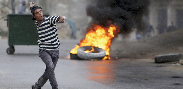 A Palestinian hurls stones at Israeli troops during clashes in the West Bank village of Siu2019eer yesterday.