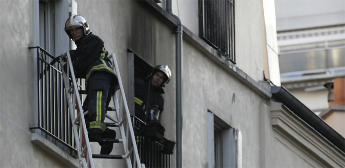 Firefighters work at the scene where a fire in an apartment building in the north of Paris killed eight people