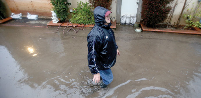 A resident helps his neighbour (not seen) battle floodwaters in her backyard in Azusa, California.