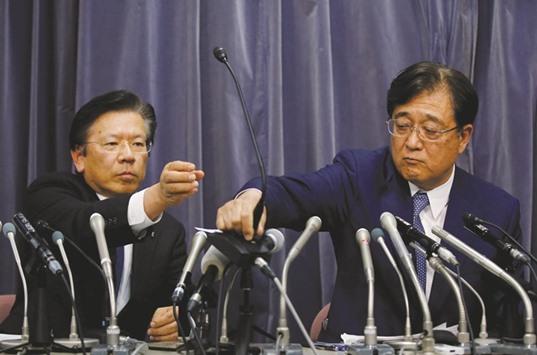 Mitsubishi Motors chairman of the board and CEO Osamu Masuko (right) passes a microphone to president Tetsuro Aikawa during a news conference in Tokyo yesterday. Analysts have estimated that the Japanese carmaker may have to pay close to $1bn to compensate Japanese mini-vehicle customers over lost u2018eco-caru2019 tax breaks and extra fuel costs.