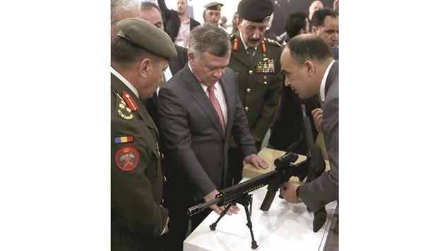 King Abdullah II of Jordan checks a machine gun as he attends the Special Operations Forces Exhibition and Conference (SOFEX) in Amman yesterday.