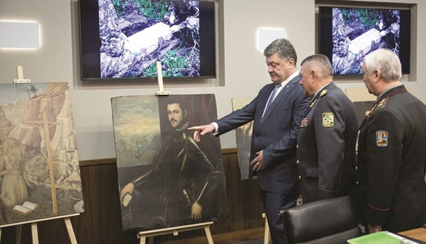 Poroshenko (left) being briefed on how the stolen paintings were recovered.