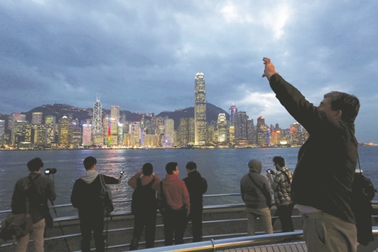 Visitors take photos on the waterfront of Kowloon peninsula facing Victoria Harbour and Hong Kong island. The trade-dependent Hong Kong economy contracted 0.4% in the first quarter.