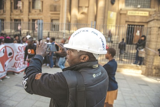 A supporter of miners films a protest outside the South Gauteng High Court in Johannesburg, after the judge allowed a multi-million-dollar class action against mining companies over an often-fatal respiratory disease contracted at work.