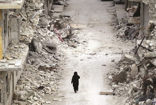 A woman walks past damaged buildings in the rebel-controlled area of Maaret al-Numan town in Idlib province, Syria on Friday. Laws meant to stop banks from providing services to terrorists, criminals and firms that do business in sanctioned states are having an unanticipated impact on relief efforts, according to more than a dozen interviews with aid directors, senior bankers, lawmakers and industry experts. More than half of the 170 local and regional banks surveyed by the World Bank last year reported losing their relationships with global partner banks. Banks also have closed accounts for hundreds of money-transfer firms that provide lifelines to migrants and their families in the $582bn remittance business.