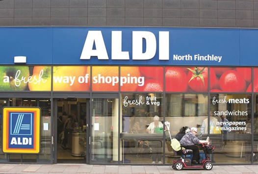 A woman using a motorised cart, sits outside the entrance to an Aldi supermarket store in London. Rising competition has pushed the retail giant to move away from its u201chard discountu201d industrial look that promised savings towards a luxurious customer experience.