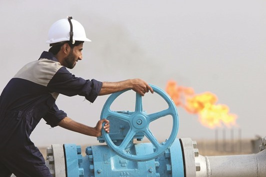 A worker checks a valve of an oil pipe at the Nasiriya oilfield in Nasiriya province, southeast of Baghdad. For Iraq, the oil challenge is compounded by a costly war against IS militants.