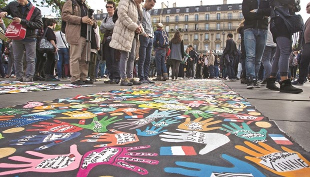 People look at a colourful banner as they gather yesterday for the general assembly of the u2018Nuit Deboutu2019 (Up All Night) movement against the French governmentu2019s proposed labour reforms at the Place de la Republique in Paris. The Nuit Debout movement has launched a call for everyone to u2018occupy public spaces worldwide, to gather together, express themselves and take back politics into their handsu2019 entitled u2018Global Deboutu2019.