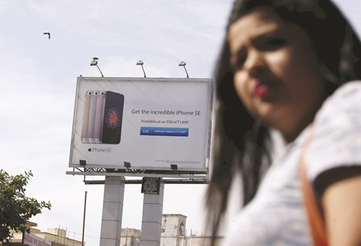A commuter walks past an Apple iPhone SE billboard in Mumbai. Apple chief executive officer Tim Cook, who begins his multiday India visit today, will unveil a development centre for digital maps in Hyderabad and introduce an accelerator programme for iOS developers in Bangalore, a person with knowledge of the trip said.