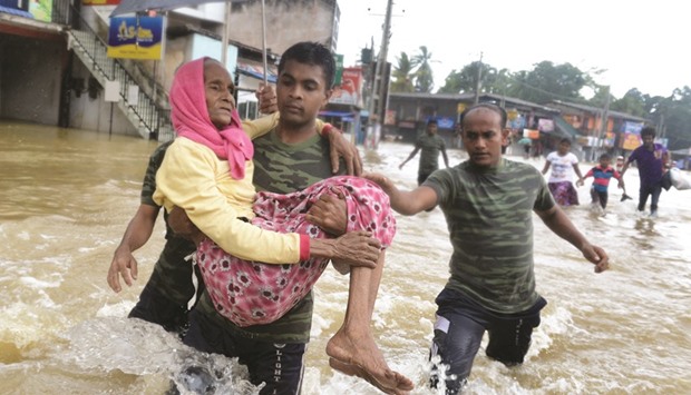 A Sri Lankan Army rescue team carrying a woman to safety through floodwaters in the suburb of Kaduwela in capital Colombo yesterday.