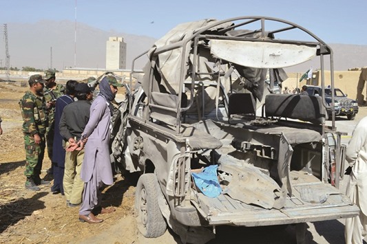 People gather around a destroyed police vehicle at the blast site in Quetta, southwest Pakistan, yesterday. At least one policeman was killed and five others were injured when their vehicle was hit by a blast in Pakistanu2019s southwest Quetta city yesterday morning, local Urdu media reported.