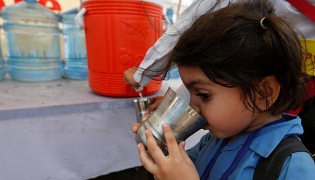 A girl drinks water at a water distribution point set up on a street corner as preparations are made in case of another heat wave in Karachi.
