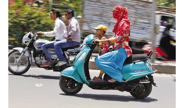 A woman shields her face from the sun as she rides her scooter in Ahmedabad yesterday.