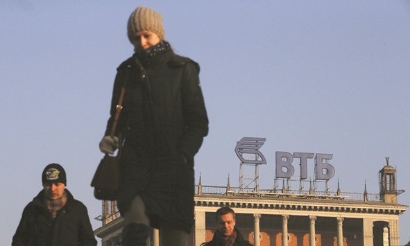 People walk past a logo of VTB Bank displayed on the roof of a building in Moscow. The privatisation of a part of the state-owned stake in VTB Bank might be completed in the autumn of this year.