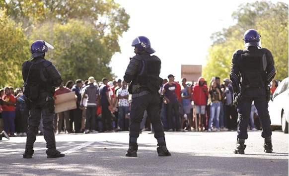 South African police stand in a street during a student protest ahead of the start of the celebrations of the centenary anniversary of Fort Hare University, in Alice, Eastern Cape province.