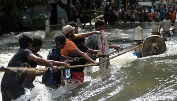Flood-affected Sri Lankans struggle to cross a torrent of floodwaters in Kelaniya, on the outskirts of Colombo, on Saturday.