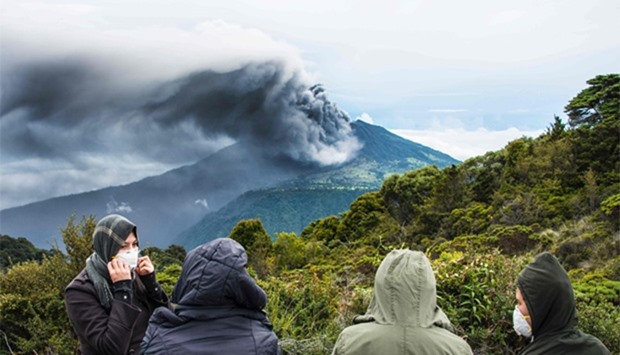 People look at the volcano as it spewes ashes