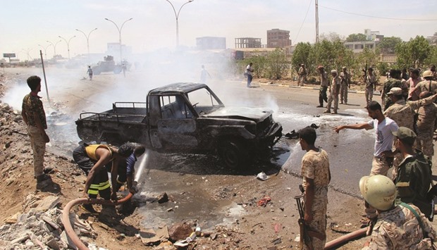 Soldiers extinguish a fire on a pick-up truck at the site of a car bomb attack in a central square in Aden yesterday, that targeted the cityu2019s security chief for the second time in a week.