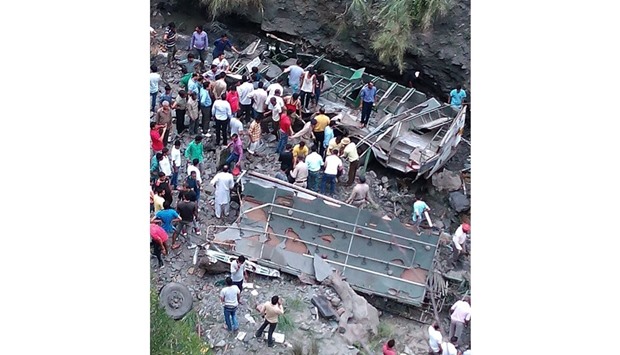 People gather beside the wreckage of a bus which fell into a gorge near Dalhousie in Chamba District of  Himachal Pradesh on Friday.