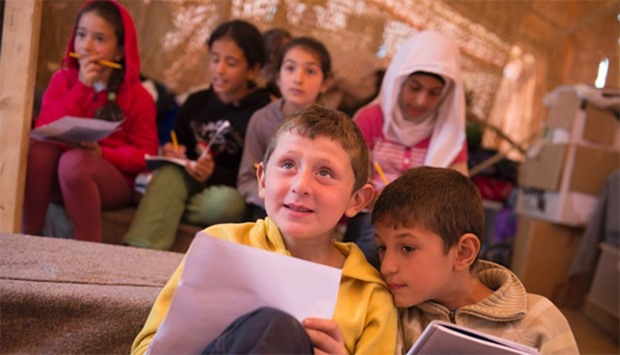 Children attend an English lesson inside a refugees camp